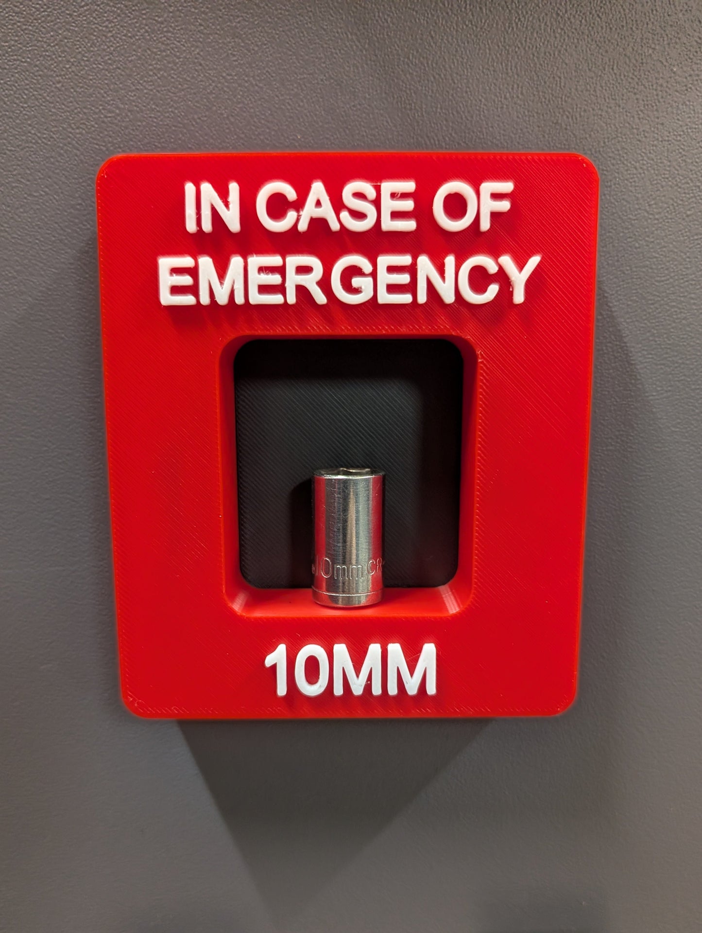 Red emergency tool box with a 10mm drill bit on a gray background