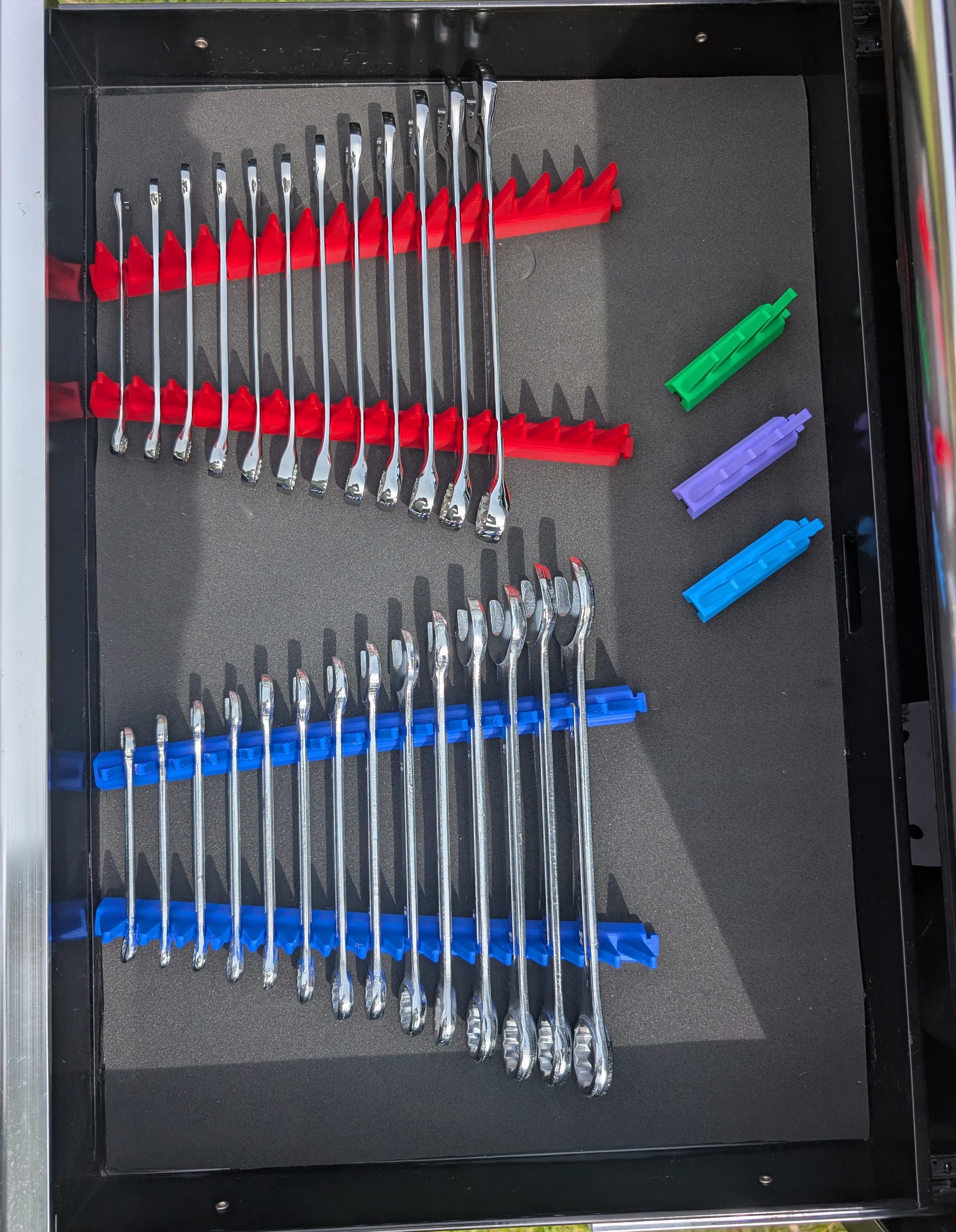 Red and blue modular spanner organisers installed in a toolbox drawer for efficient wrench storage and organisation.