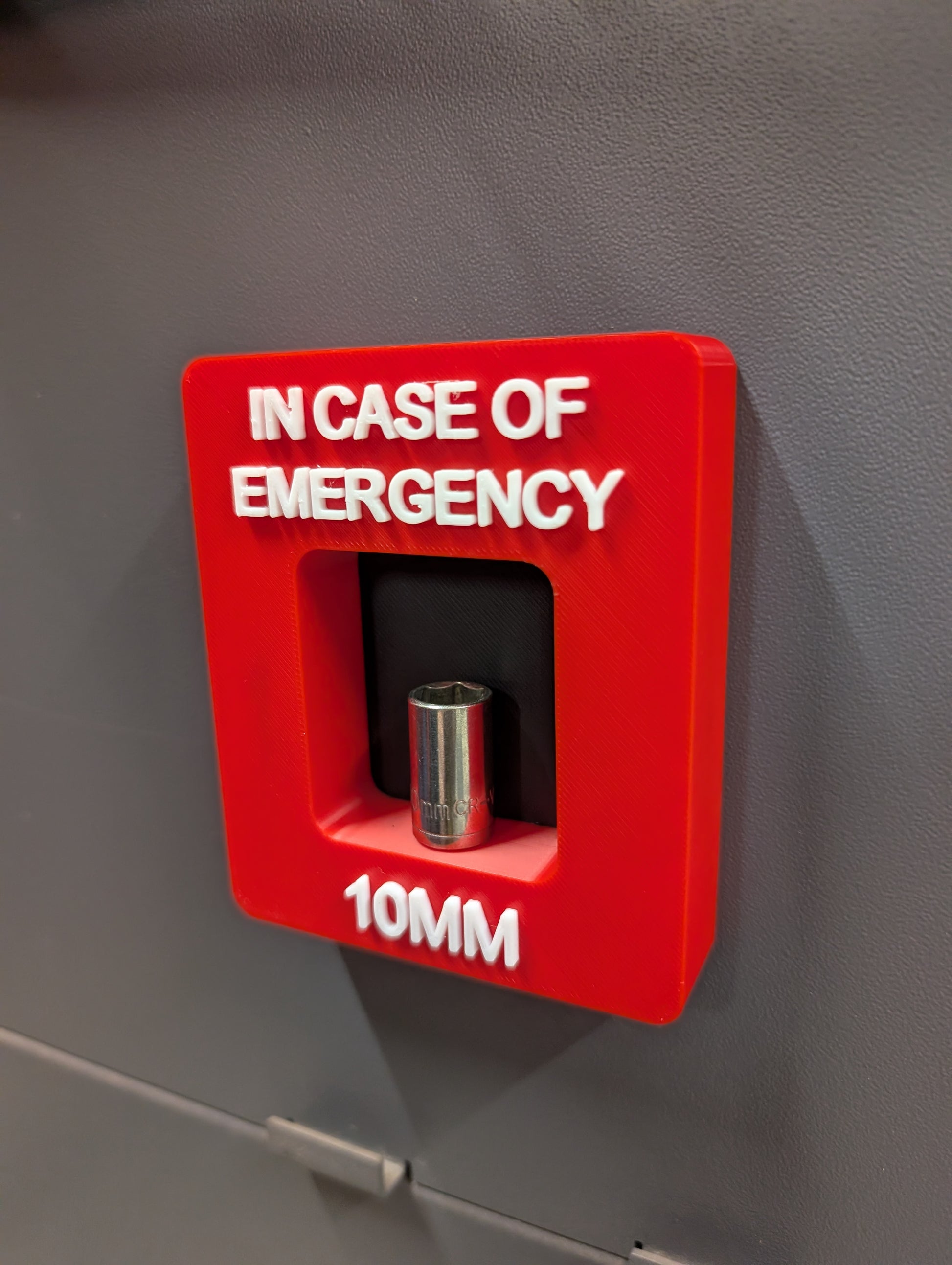 Red emergency tool box with a 10mm socket on a gray background
