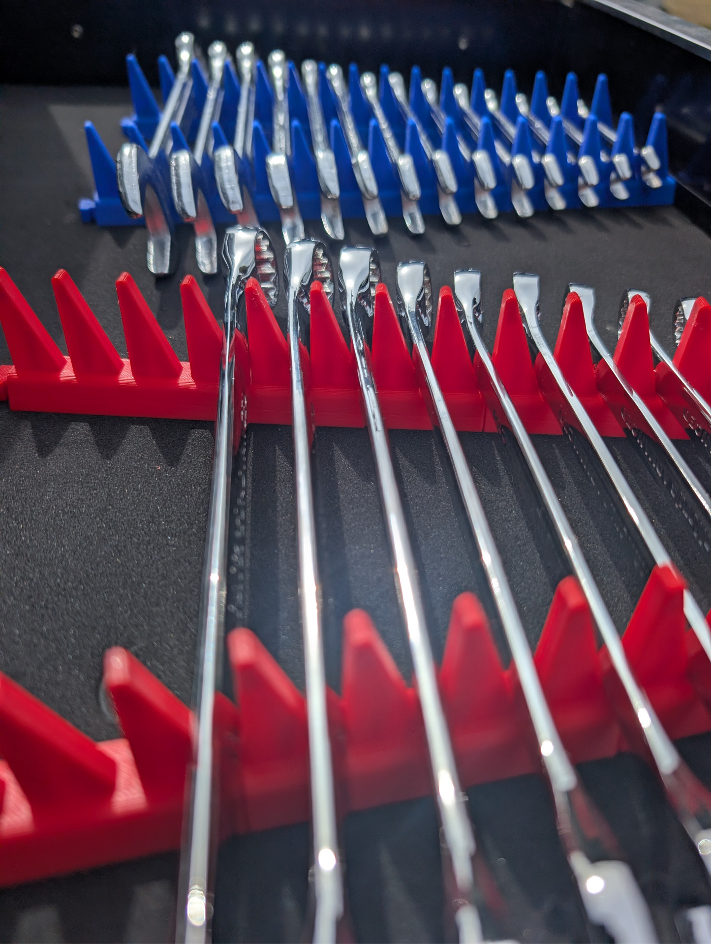 Set of wrenches with red and blue holders on a black toolbox